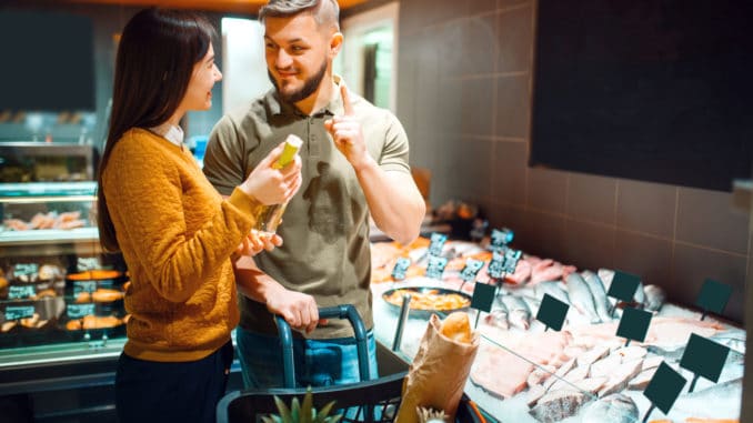 Family couple choosing oil for cooking fish in grocery store. Man and woman with cart buying beverages and products in market, customers shopping food and drinks