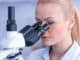 Girl with a slide for the microscope University Hospital. Attractive young scientist looking at the microscope slide in the forensic laboratory.