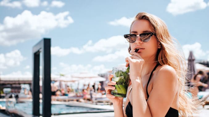 Young hot woman resting at swimpool. relaxed girl drinking cocktail and enjoy her time in resort spa place ouside