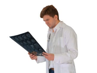 Concentrated male doctor looking at computed tomography xray image on white background.