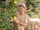 Smiling man in straw hat pruning lemon tree in the garden
