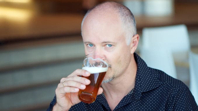 Middle aged man drinking beer from a glass in a pub, a bar or a restaurant