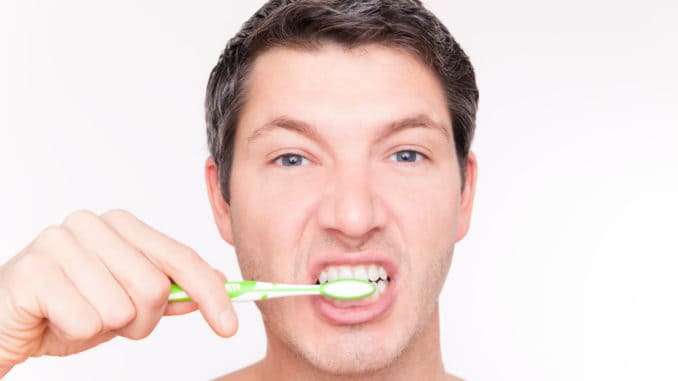 Teeth brushing man looking in mirror