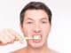 Teeth brushing man looking in mirror