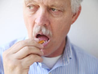 Front view of man taking a dietary supplement