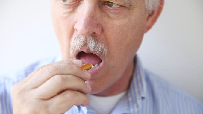 Front view of man taking a dietary supplement