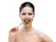 Woman with red lipstick eating broccoli on the stainless fork, isolated on white. Fresh and healthy dieting food