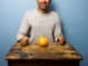 Healthy young man having a grapefruit for dinner at old table