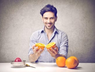 Young man holding an orange to do an orange juice