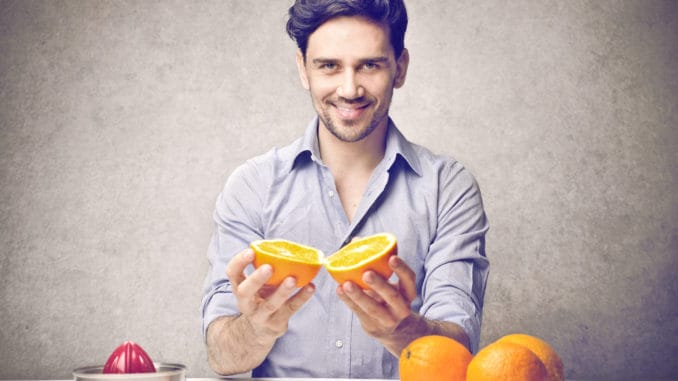 Young man holding an orange to do an orange juice