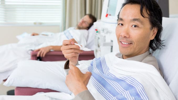 Portrait of male cancer patient eating crushed ice during dialysis at hospital room