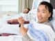 Portrait of male cancer patient eating crushed ice during dialysis at hospital room