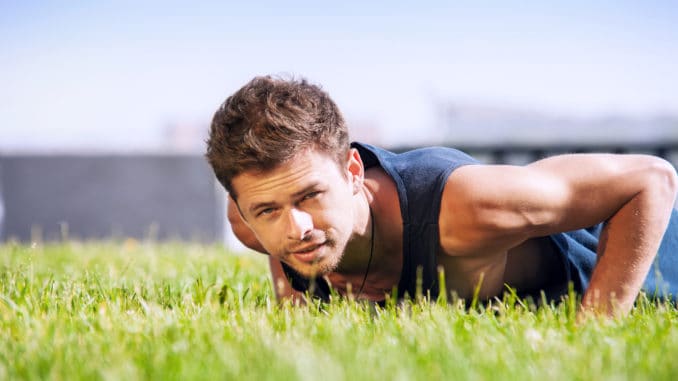 Healthy young man doing pushups outdoors