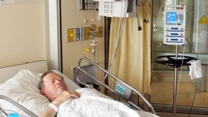 Senior man lying in hospital bed getting oxygen in intensive care unit