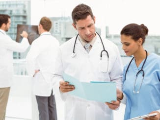 Male doctor and surgeon looking at reports in the medical office