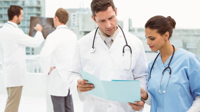 Male doctor and surgeon looking at reports in the medical office