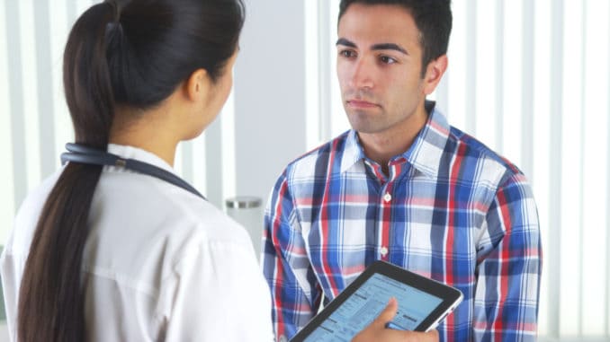 Chinese doctor talking to patient and taking notes in the office