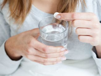 Horizontal view of ill woman taking aspirin