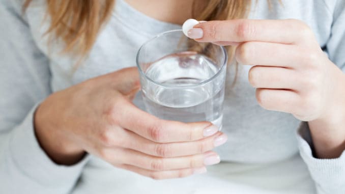 Horizontal view of ill woman taking aspirin