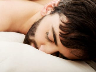 Young exhausted man sleeping in bed.