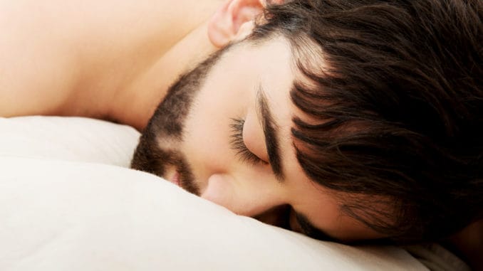 Young exhausted man sleeping in bed.