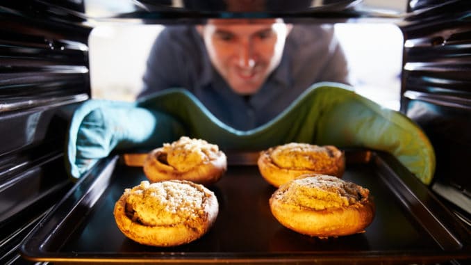 Man Putting Stuffed Mushrooms Into Oven To Cook