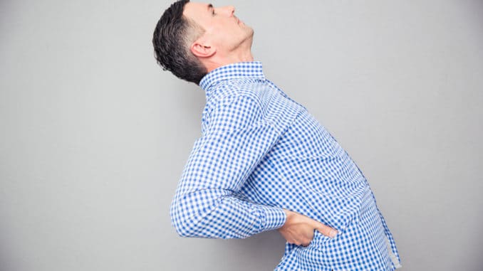 Man having a back pain over gray background