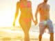 Summer beach couple romantic holding hands at sunset walking in love on honeymoon travel vacation holidays.