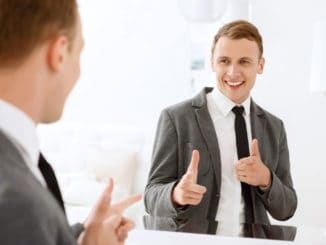 You are winner. Smiling man looking in mirror and pointing on himself with help of his index fingers.
