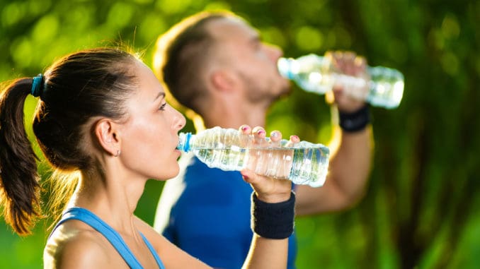 Man and women drinking water from bottle after fitness sport exercise.