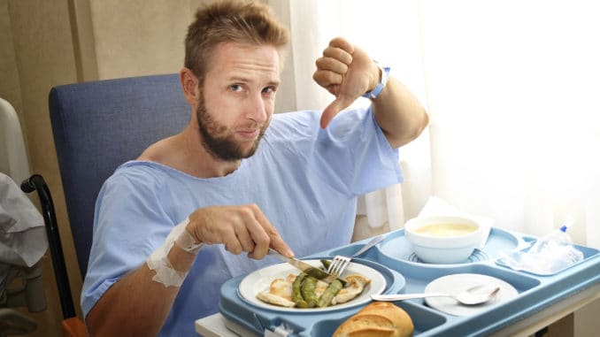 man in hospital room eating healthy diet clinic food in upset moody face expression Young man in hospital room