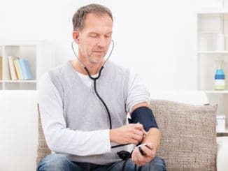 Man Sitting On Couch Checking His Own Blood Pressure
