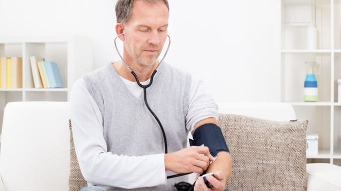 Man Sitting On Couch Checking His Own Blood Pressure