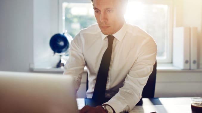 Young white business man working on computer sitting at his desk