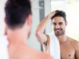 Handsome shirtless man looking in the mirror