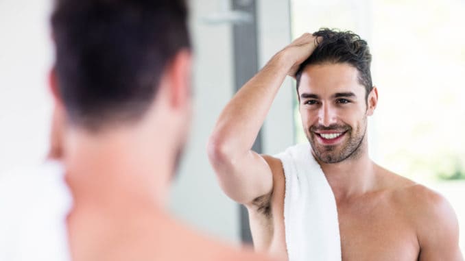 Handsome shirtless man looking in the mirror in the bathroom Handsome shirtless man looking in the mirror