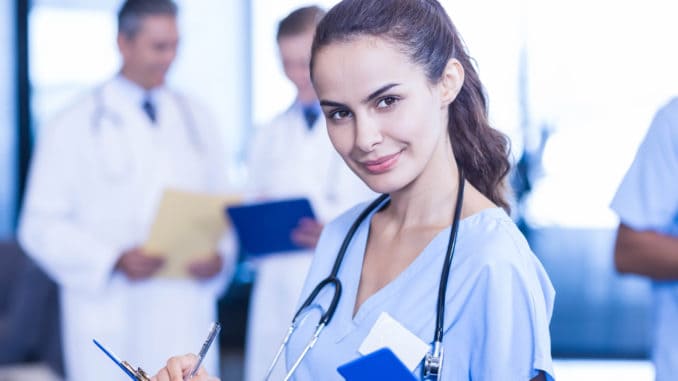 Female doctor writing a medical report and colleagues standing behind