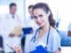 Female doctor writing a medical report and colleagues standing behind