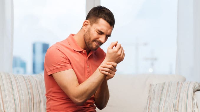 dreamstime_m_68060460 People, healthcare and problem concept - unhappy man suffering from pain in hand at home