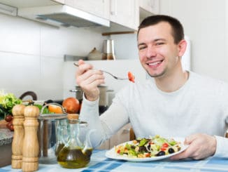 Happy adult guy having healthy lunch with the veggies at the home