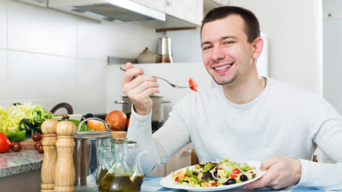 Happy adult guy having healthy lunch with the veggies at the home