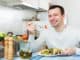 Happy adult guy having healthy lunch with the veggies at the home