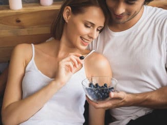 Man holding bowl of blueberries for his woman