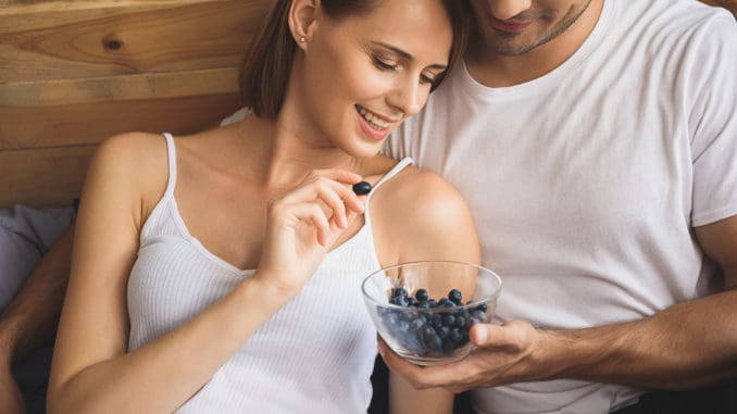 Man holding bowl of blueberries for his woman