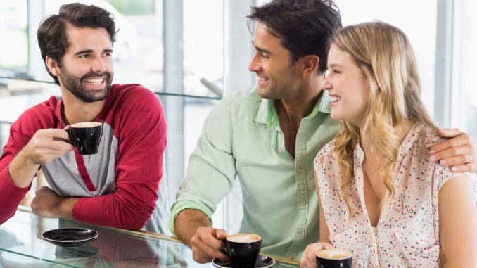 Smiling women and two men having cup of coffee in cafe