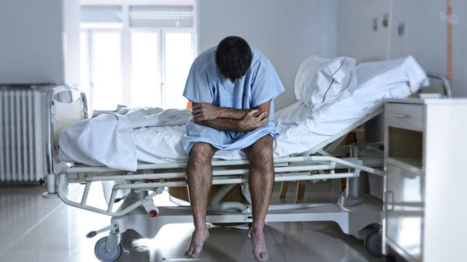 Young desperate man sitting at hospital bed alone