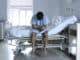 Young desperate man sitting at hospital bed alone