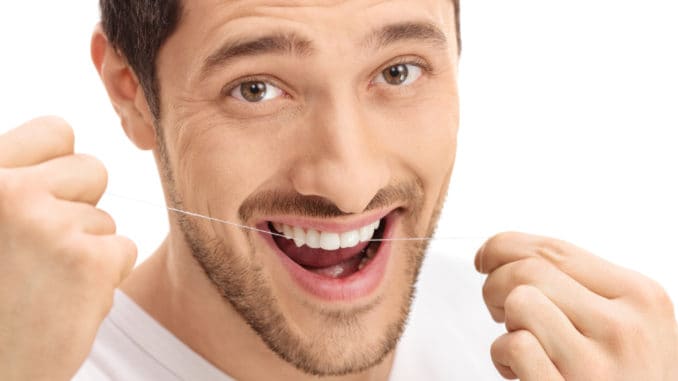Man flossing his teeth isolated on white background