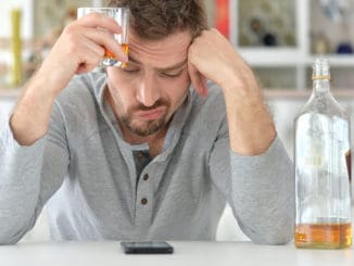 Young man drinking alcohol, in bad mood