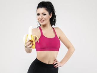 Attractive fit woman eating banana, isolated on Background.